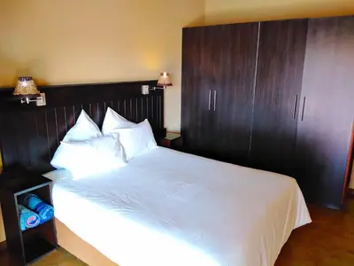 a bedroom with a large white bed with a wooden headboard at Zebula Golf and Wildlife Estate - Njala Crossing Pax 13 - Moi Signature Luxury villa in Mabula