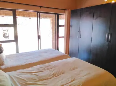 a bedroom with two beds and a large window at Zebula Golf and Wildlife Estate - Njala Crossing Pax 13 - Moi Signature Luxury villa in Mabula