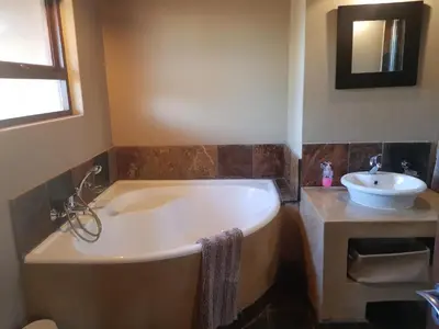 a bathroom with a tub and a sink at Zebula Golf and Wildlife Estate - Squirrel Pandemonium Pax 12 - Moi Signature Luxury villa in Mabula