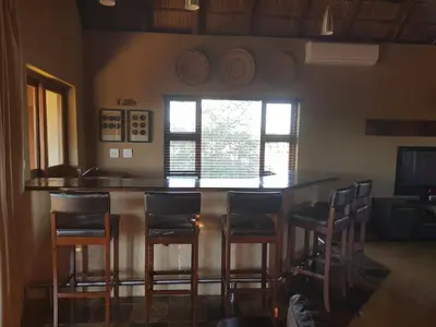 a kitchen with a bar with stools and a window at Zebula Golf and Wildlife Estate - Squirrel Pandemonium Pax 12 - Moi Signature Luxury villa in Mabula