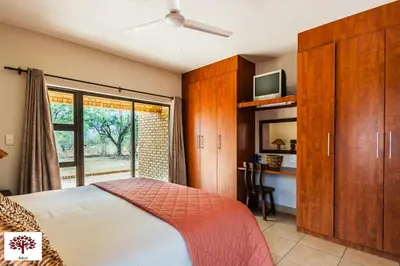 a bedroom with a bed and a desk and a window at Zebula Golf and Wildlife Estate - Spectacular View Pax 13 - Moi Signature Luxury villa in Mabula