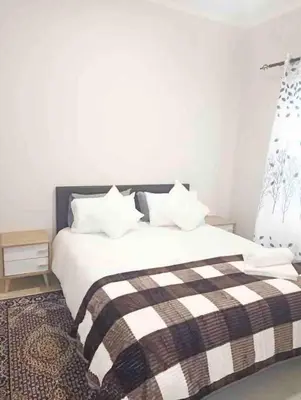 a bedroom with a bed with a black and white blanket at Blest5 Tranquil Stay in Midrand