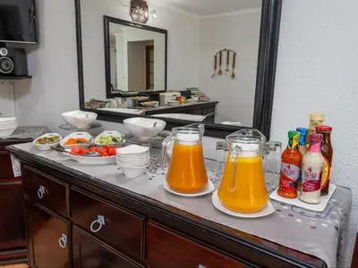 a buffet with drinks and plates of food on a table at Kuiersaam Guesthouse Luxurious & Mordern Accommodation in Secunda