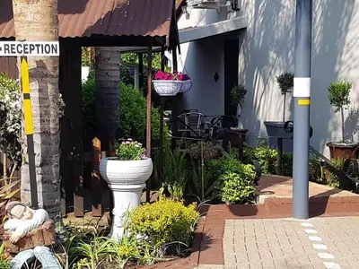 a white toilet sitting outside of a house with plants at Kuiersaam Guesthouse Luxurious & Mordern Accommodation in Secunda