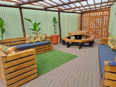 a patio with wooden benches and a picnic table at Kuiersaam Guesthouse Luxurious & Mordern Accommodation in Secunda