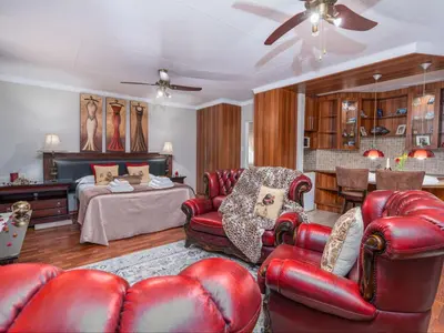 a living room with red leather furniture and a bed at Kuiersaam Guesthouse Luxurious & Mordern Accommodation in Secunda