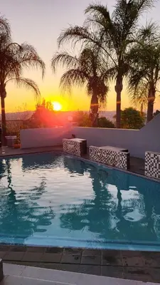 a swimming pool with a sunset in the background at The Concept in Centurion