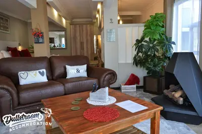 a living room with a brown couch and a table at Misty View Apartments in Dullstroom