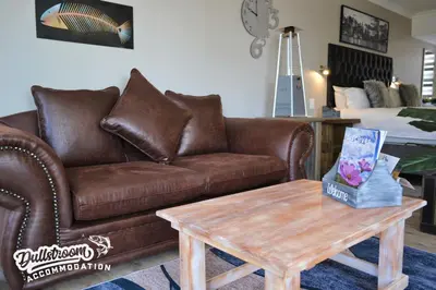 a living room with a brown couch and a coffee table at Misty View Apartments in Dullstroom