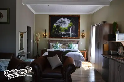 a bedroom with a bed and a couch and a chair at Misty View Apartments in Dullstroom
