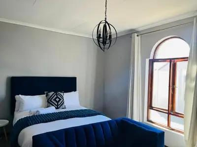 a bedroom with a blue bed and a window at Budget-Friendly & Cozy Haven by BK Hospitable in Midrand