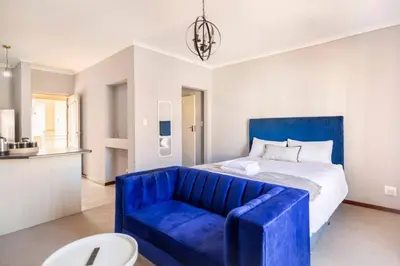 a bedroom with a blue couch in front of a bed at Budget-Friendly & Cozy Haven by BK Hospitable in Midrand