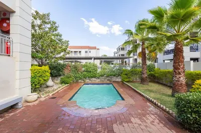 a swimming pool in a yard with palm trees at Budget-Friendly & Cozy Haven by BK Hospitable in Midrand