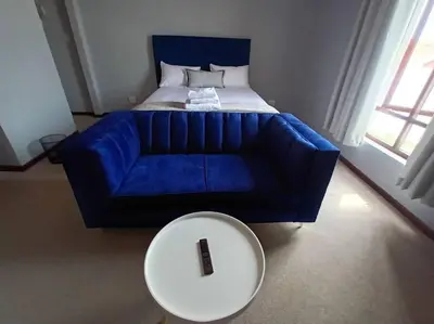 a blue couch with a white table and a bed at Budget-Friendly & Cozy Haven by BK Hospitable in Midrand