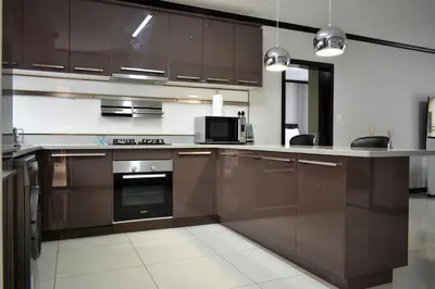 a kitchen with brown cabinets and a microwave at Candymore luxury apartment in Midrand