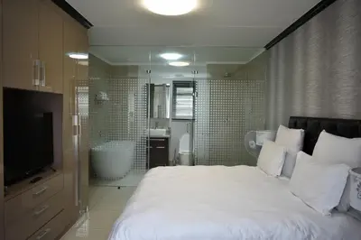 a bedroom with a large white bed and a bathroom at Candymore luxury apartment in Midrand