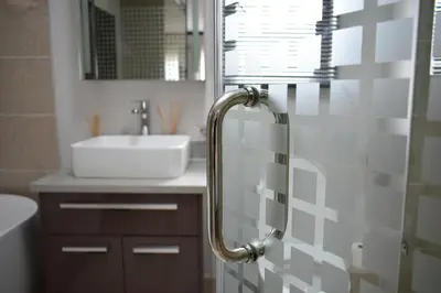 a bathroom with a sink and a glass shower door at Candymore luxury apartment in Midrand