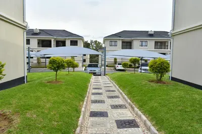 a walkway in a yard with two trees and umbrellas at Candymore luxury apartment in Midrand