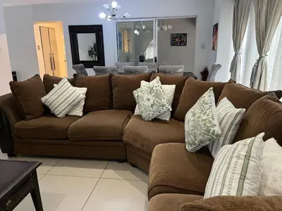 a brown couch with pillows on it in a living room at 3 bedroom self catering @ Lelapa La Baphogole in Pretoria