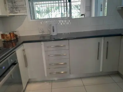 a kitchen with white cabinets and a sink and a mirror at 3 bedroom self catering @ Lelapa La Baphogole in Pretoria
