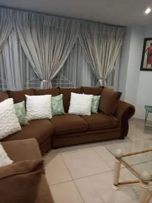 a brown couch with white pillows in a living room at 3 bedroom self catering @ Lelapa La Baphogole in Pretoria