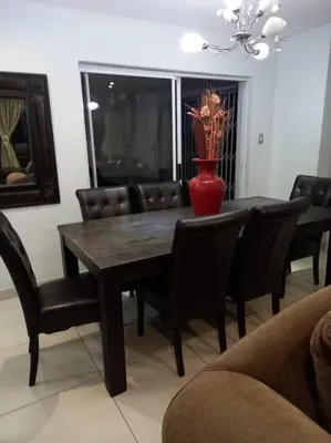a dining room table with chairs and a red vase on it at 3 bedroom self catering @ Lelapa La Baphogole in Pretoria