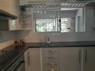 a kitchen with white cabinets and a large mirror at 3 bedroom self catering @ Lelapa La Baphogole in Pretoria
