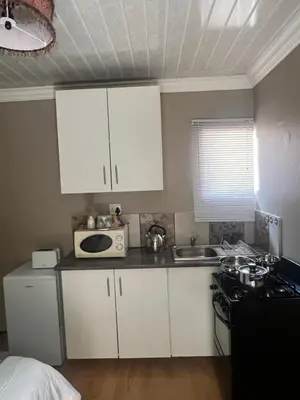 a small kitchen with white cabinets and a microwave at 17 Byvanger Luxury Home Deluxe Queen Suite Room 1 in Centurion