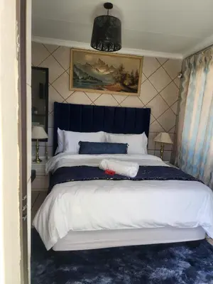 a bedroom with a large bed with a blue headboard at 17 Byvanger Luxury Home Deluxe Queen Suite Room 1 in Centurion