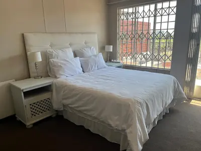 a bedroom with a large white bed with a window at Executive suite@Lofts in Pretoria