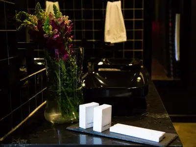a bathroom counter with a vase of flowers and cards at Milner Fashion House in Pretoria