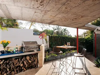 an outdoor kitchen with a grill and a table and chairs at Milner Fashion House in Pretoria