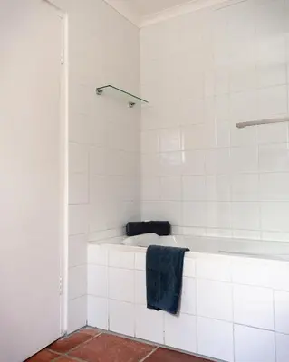 a white tiled bathroom with a tub and a towel at The Lofts @ Ivy Lane in Dullstroom