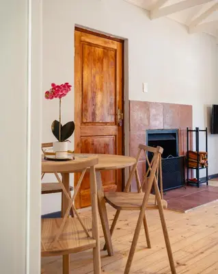 a table and chairs in a room with a fireplace at The Lofts @ Ivy Lane in Dullstroom