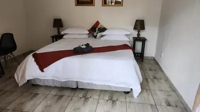a bedroom with a large white bed with two bags on it at SABLE INN B&B in Modimolle