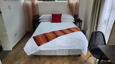 a bedroom with a bed with a red pillow on it at SABLE INN B&B in Modimolle