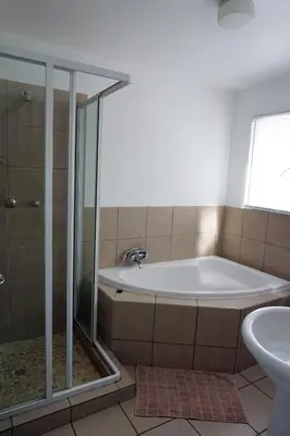 a bathroom with a tub and a shower and a sink at Sheba Rock Guesthouse in Nelspruit