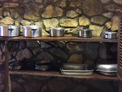 a shelf with pots and pans and a stone wall at Sheba Rock Guesthouse in Nelspruit