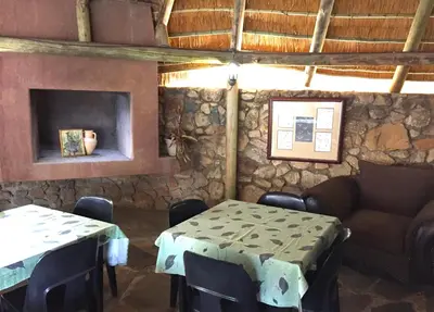 a room with a couch and tables and a fireplace at Sheba Rock Guesthouse in Nelspruit