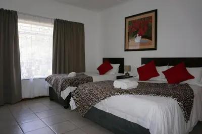 a hotel room with two beds and a window at Sheba Rock Guesthouse in Nelspruit