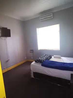 a room with two beds and a large window at Prime Guest Inn in Benoni