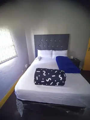 a bedroom with a white bed with a blue headboard at Prime Guest Inn in Benoni