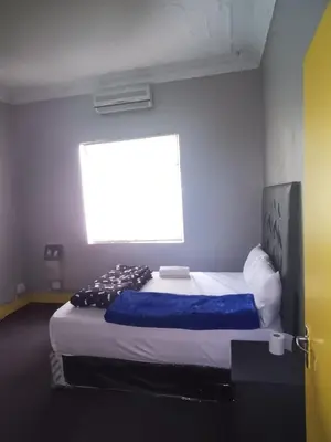 a bedroom with a large bed with a large window at Prime Guest Inn in Benoni