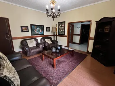 a living room with leather furniture and a chandelier at Limpopo Guest Manor in Polokwane