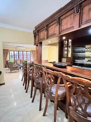 a large room with a long bar with wooden chairs at Limpopo Guest Manor in Polokwane