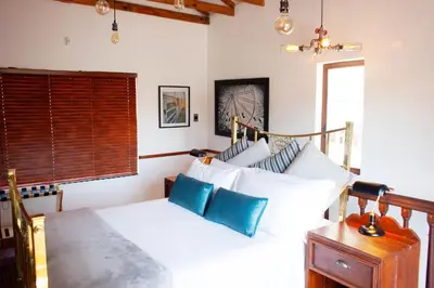 a bedroom with a bed with white sheets and blue pillows at The Blue Place in Pretoria