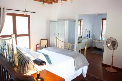 a bedroom with a bed and a bathroom with a sink at The Blue Place in Pretoria