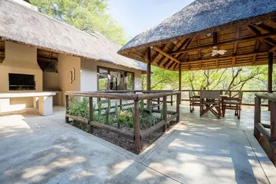 a pavilion with a table and a thatched roof at Raptors Lodge in Hoedspruit