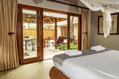 a bedroom with a bed and a patio with a table at Raptors Lodge in Hoedspruit