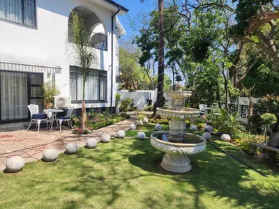 a garden with a fountain in the middle of a yard at C'est La Vie Boutique Hotel in Witbank